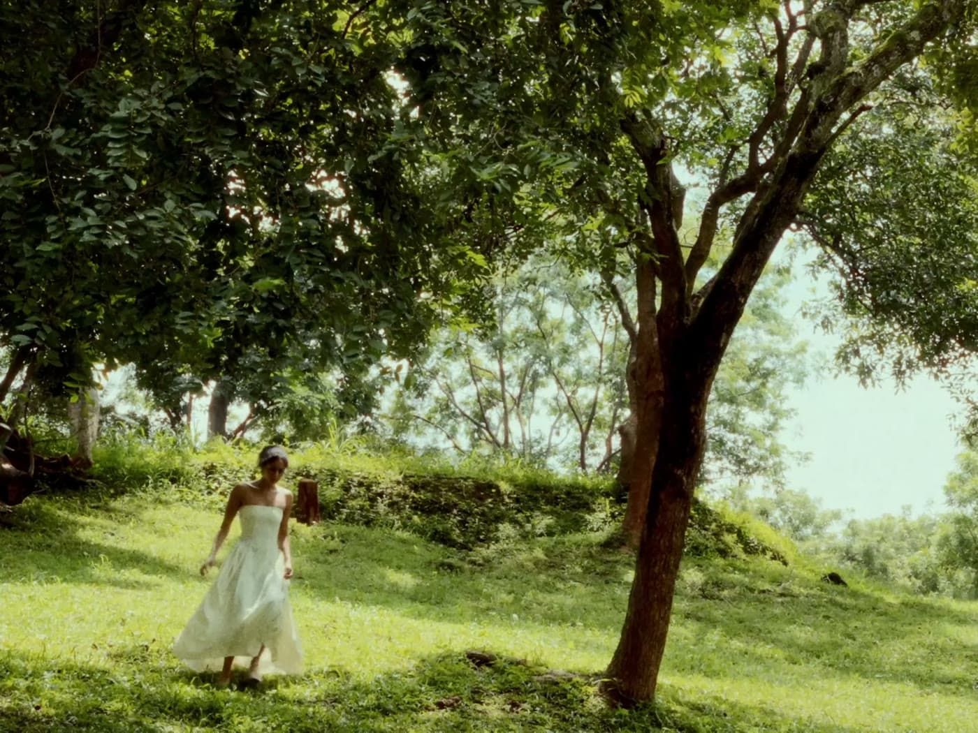 Rachel in a white dress beneath the trees, in a scene from What Will Become of the Woman?